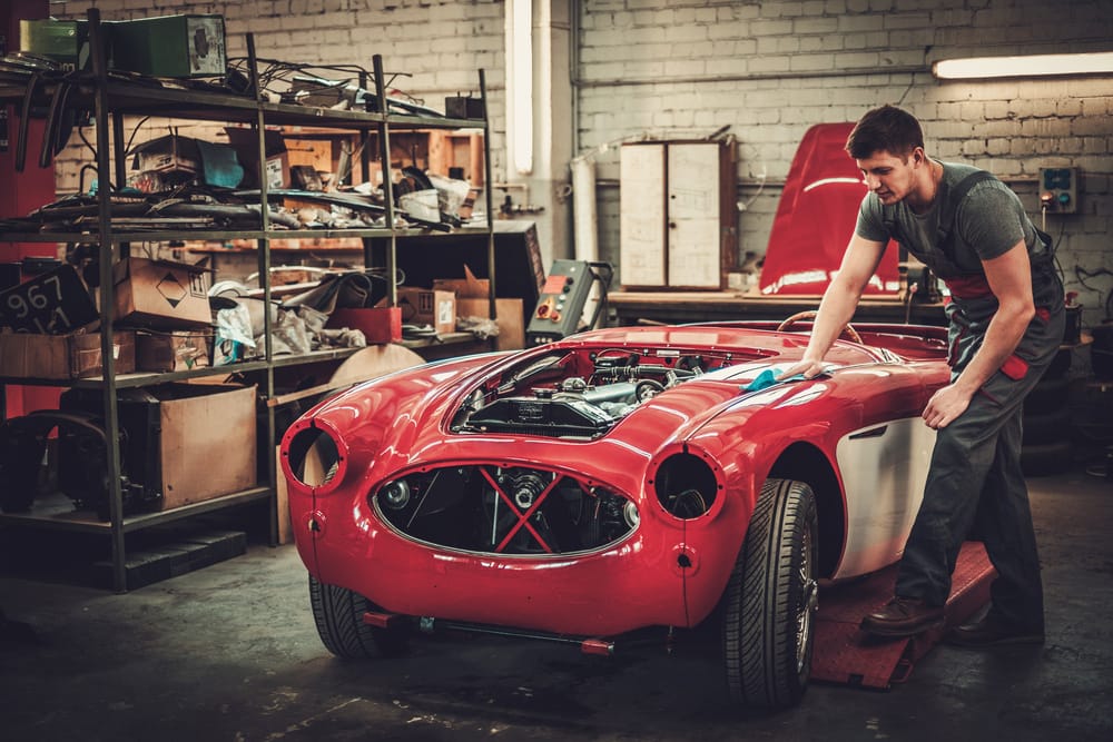 Mechanic polishning car in restoration workshop.